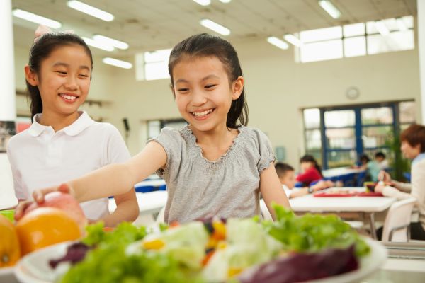 desperdício de alimentos nas escolas duas alunas sorrindo com um prato de salada