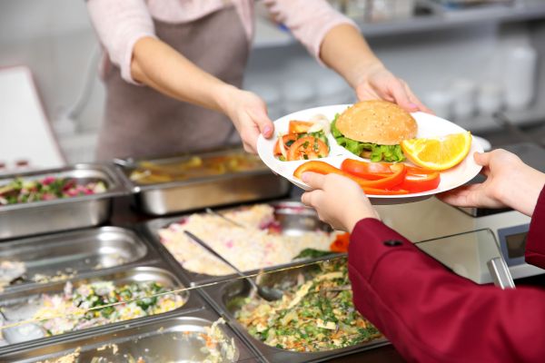 desperdício de alimentos nas escolas mulher dando bandeja de alimento com comida no prato para aluno