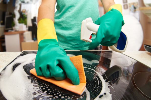 limpar fogão produtos pessoa com luva verde limpando fogão
